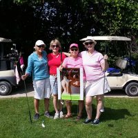 Four women in front of a golf cart